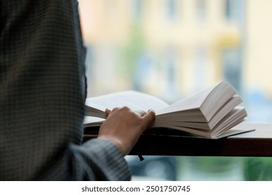 close up hand hold book in bookstore near the window a beautiful student is sitting reading books preparing for exams in front of the window - Powered by Shutterstock