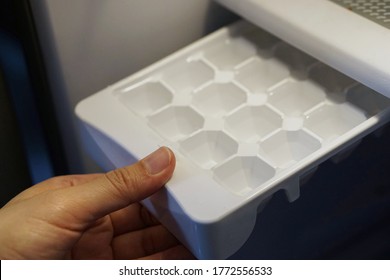 Close Up Hand Hold Ice Tray Making Ice Cubes In Freezer.