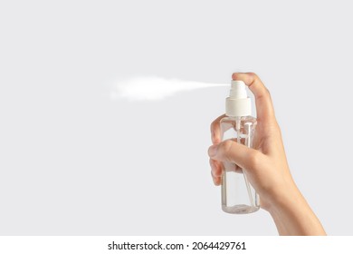 Close Up Hand Hold Small Spray Bottle And Spray On White Background.