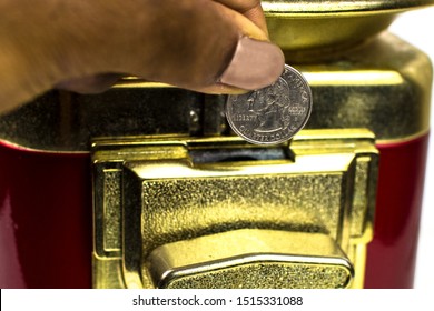 Close Up Of A Hand Holding A 25 Cent USD Quarter Before Inserting It Into A Coin Operated Red & Gold Candy Gumball Vending Machine Mechanism