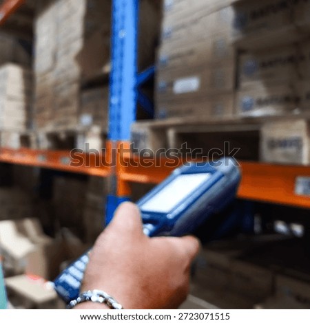 Close up hand holding barcode scanner in warehouse. Worker checking inventory with PDA device. Logistics, supply chain and distribution concept.