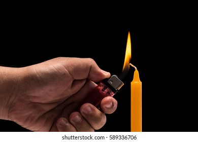 Close Up Hand Holding Burning Gas Lighter To Light Candle. Studio Shot Isolated On Black Background.