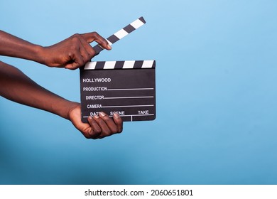 Close up of hand holding clapperboard in studio. Person with chalkboard used to cut scenes for movies and cinematography industry. Adult showing movie clapboard for film production