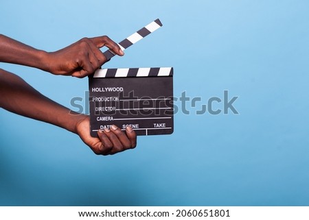 Close up of hand holding clapperboard in studio. Person with chalkboard used to cut scenes for movies and cinematography industry. Adult showing movie clapboard for film production