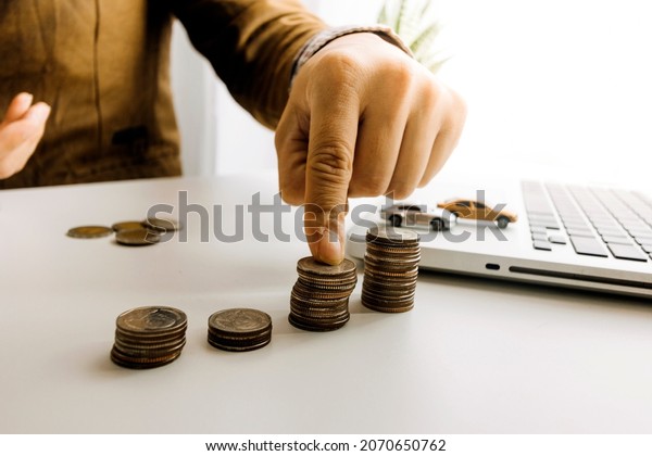 close up hand holding coin, stack of money and\
toy car on table, saving for future, manage to success transport\
business technology\
concept