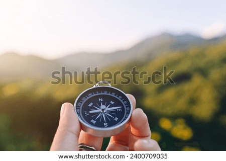 close up hand holding compass with mountain and sky background, travel and relaxation, planning and manage to success business concept
