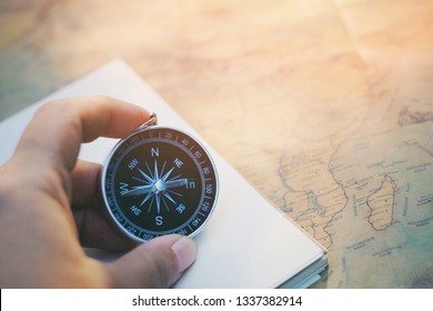 close up hand holding compass and notebook on map, copy space background for text, manage to success business, travel and lifestyle concept