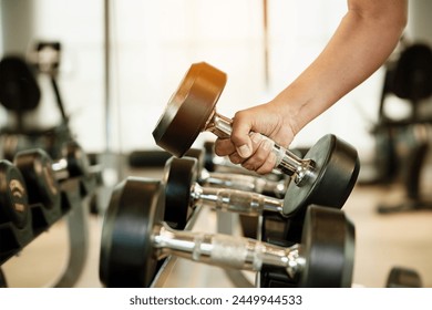 Close up hand holding dumbbell on floor in gym with woman background. Object goal weightlifting bodybuilding.  - Powered by Shutterstock