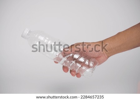 Close up hand holding empty plastic water bottle on white background.Man hand throwing empty plastic bottles in the recycle trash.