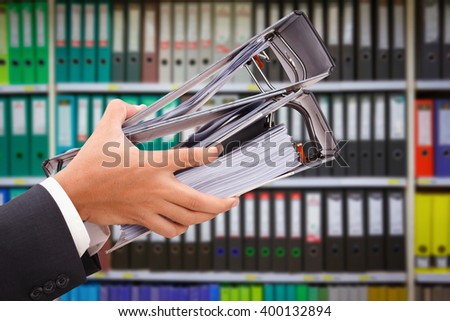 close up of hand holding file binder on office shelves