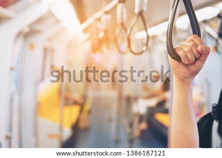 Close up of hand holding a handle on the electric train,The Bangkok Mass Transit System , known as BTS or Skytrain, is an elevated rapid transit system in Bangkok. 