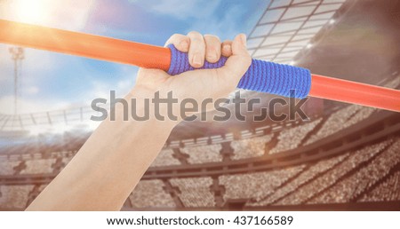 Close up of a hand holding a javelin against view of a stadium