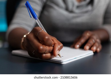 Close Up Of Hand Holding Pen To Write On Textbook File, Working From Home On Business Project. Person Using Notebook To Take Notes And Writing Information On Paper. Remote Work At Desk