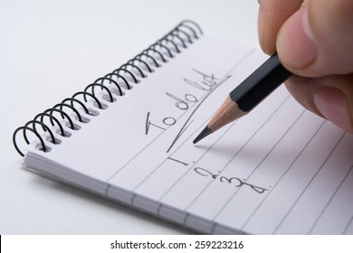 Close Up Of Hand Holding A Pencil And Writes The To Do List. Isolated On White