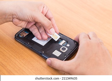 Close Up Hand Holding  SIm Card And Smartphone On Wood Background