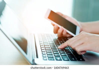 Close up of hand holding smart phone and laptop. - Shutterstock ID 1604769463