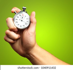 Close Up Of Hand Holding Stopwatch against a green background - Shutterstock ID 1040911432