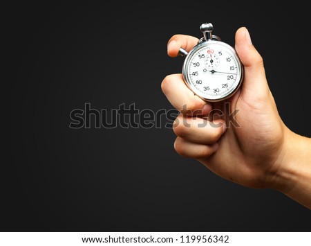 Close Up Of Hand Holding Stopwatch against a black background