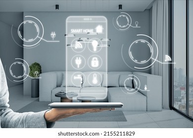 Close up of hand holding tablet with abstract digital smart home hologram on blurry living room interior background. Technology and innovation concept