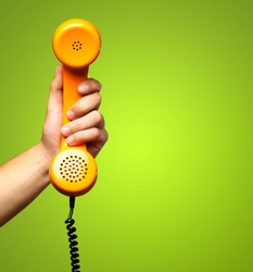 Close Up Of Hand Holding Telephone Against A Green Background