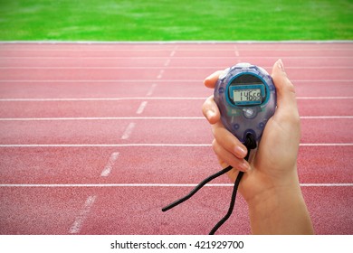 Close up of a hand holding a timer on a white background against race track