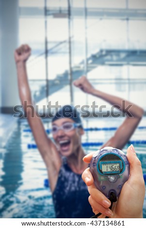 Close up of a hand holding a timer on a white background against excited swimmer jumping up the swimming pool
