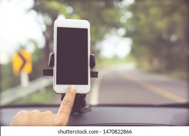 Close Up Hand Holding Using Mobile Smart Phone With Black Screen In Car Console Front Windshield Holder Stick. Insert Map Gps Navigation Travel On The In The Background Of The Dashboard. Copy Space. 