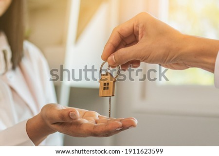 Close up hand of home,apartment agent or realtor was holding the key to the new landlord,tenant or rental.After the banker has approved and signed the purchase agreement successfully.Property concept.