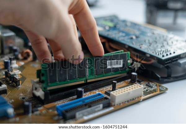 close up hand insert or install the ram\
memory component in the pc\
motherboard