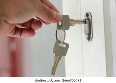 Close up of a hand inserting a key into a house door lock.