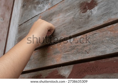 Close up of hand knocking on old wooden door.