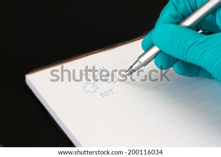  close up Hand with lab green glove writing a chemical formula of DDT isolated on black background