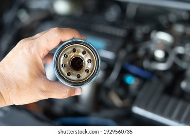 Close up hand a man hold old oil filter for car maintenance concept in engine room background