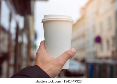 Close up of hand man is holding a cup of coffee on street city  - Powered by Shutterstock