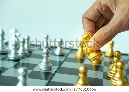 Close up of hand of man holding gold chess horse on chess board , Copy space for your text.