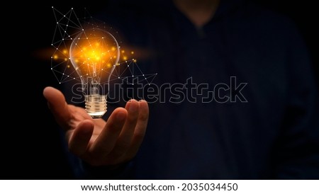 Close up hand of man holding illuminated light bulb in black background. idea, innovation, thinking, and inspiration for business concepts. Cyber digital data idea.