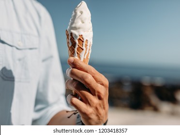 Close Up Of Hand Of Man Holding A Melting Ice Cream Cone. Man Holding An Ice Cream On Sunny Day.