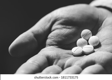 Close Up Hand Man Holding Taking Multiple Pills. Stop Drug Use Taking Medication Health Care Medical Concept. Narcotic Sleeping Pills Dark Background. Photo Black And White.