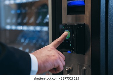 Close up hand of man pushing button on vending machine for choosing a snack or drink. Small business and consumption concept.