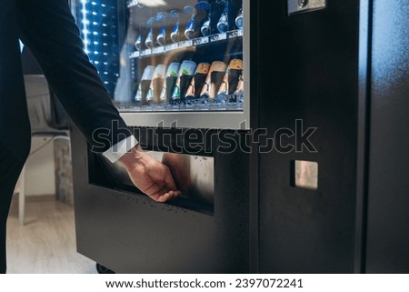Close up hand of man pushing button on vending machine for choosing a snack or drink. Small business and consumption concept.