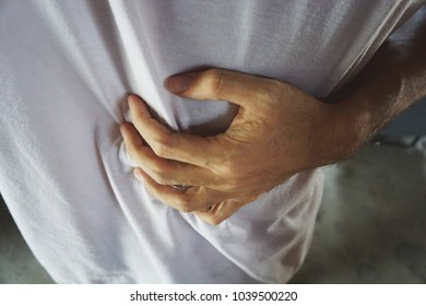 close up hand man with severe stomachache holding his stomach