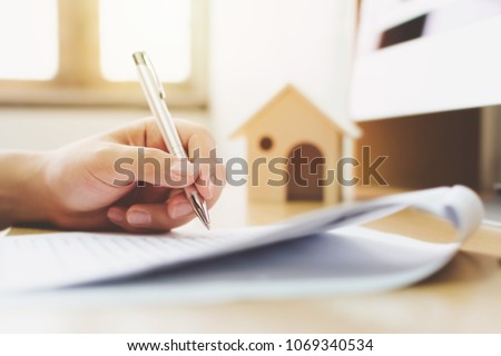 Close up hand of man signing signature loan document to home ownership. Mortgage and real estate property investment