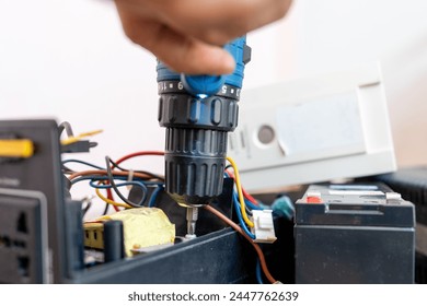 Close up Hand of man using a drill to remove the screws from the UPS battery backup for personal Computer to repairs. Electronic waste. - Powered by Shutterstock