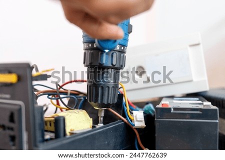 Close up Hand of man using a drill to remove the screws from the UPS battery backup for personal Computer to repairs. Electronic waste.