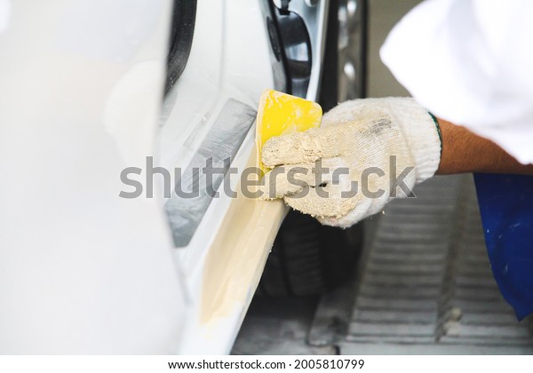 Close up Hand of man with wearing\
protective cotton glove was polish car element body after painting\
in the garage. Car repair or fix business\
concept.