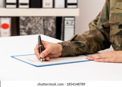 Nahaufnahme einer Hand eines Mannes, der ein Dokument auf einem Schreibtisch in der Militärakademie schreibt oder unterzeichnet