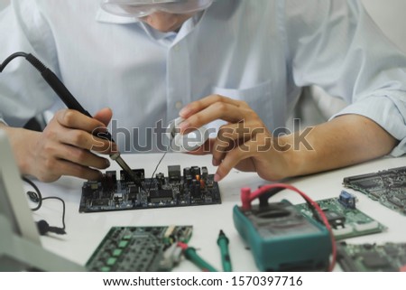 Close up of the hand men hold tool repairs electronics manufacturing Services, Manual Assembly Of Circuit Board Soldering.

