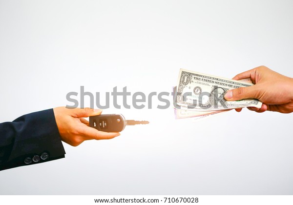 close up of Hand with money and\
car keys on a white background,finance and buying car\
concept