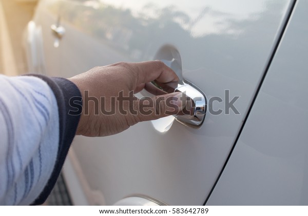 Close up of hand is\
opening car door.