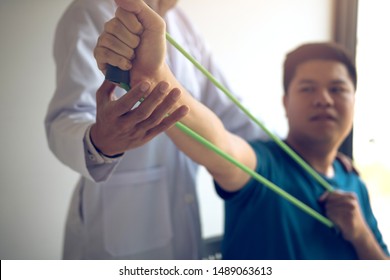 Close up hand patient doing stretching exercise with a flexible exercise band and a physical therapist hand to help in clinic room.